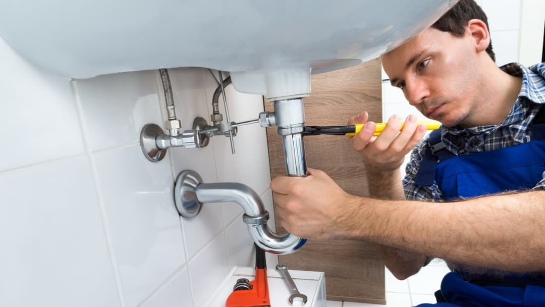Plumber repairing sink plumbing during a restoration project